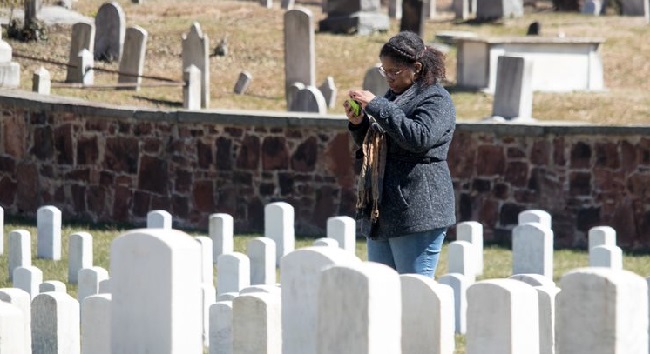 A woman stands among the headstones at a National Cemetery.